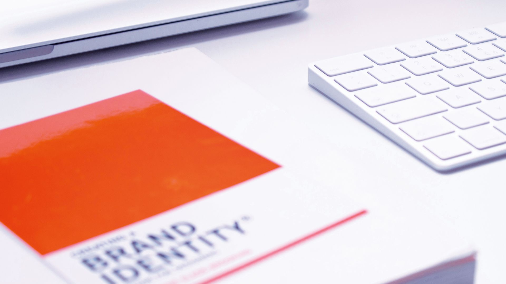 Light coloured desktop showing part of computer keyboard and Brand Identity document.