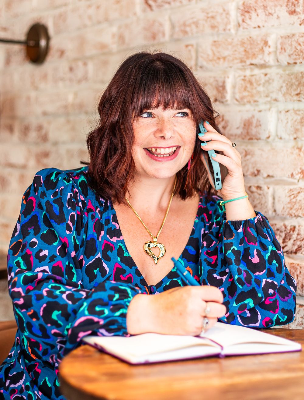 Katie Bell of KBE Partners holding a mobile phone while writing in a journal.