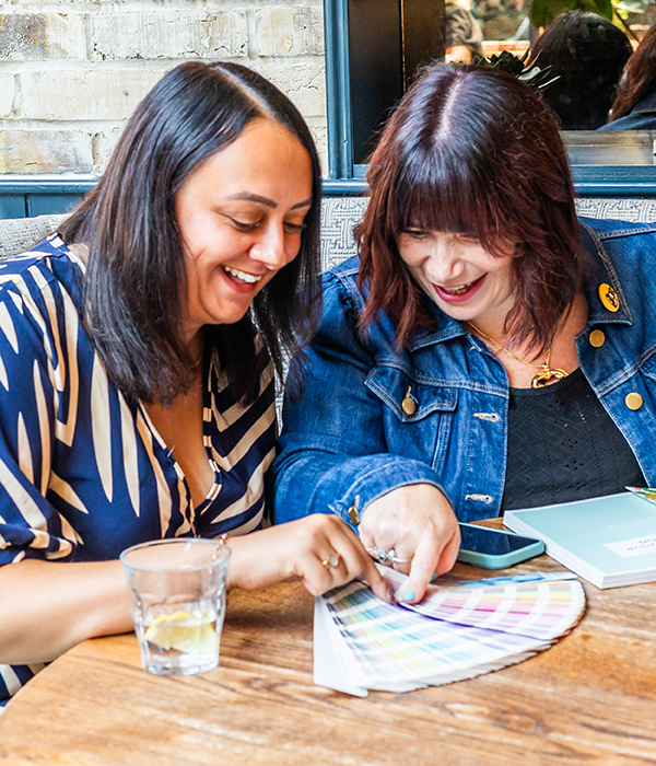 Biance Rodriguez Jacobs and Katie Bell looking at colour charts on a desk.