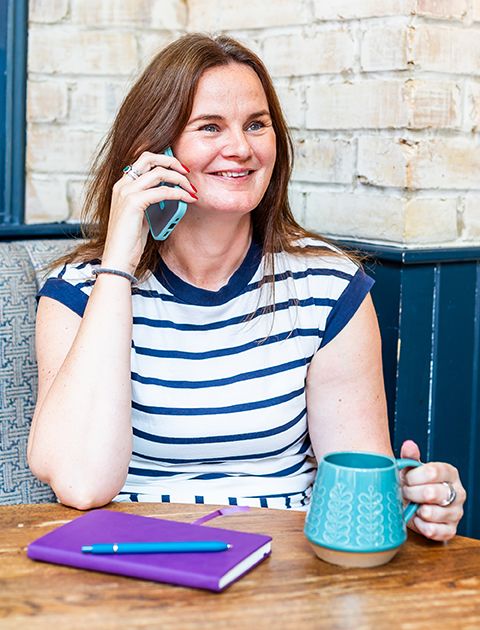 Emma Culver of KBE Partners wearing white and blue hooped dress talking on mobile phone.