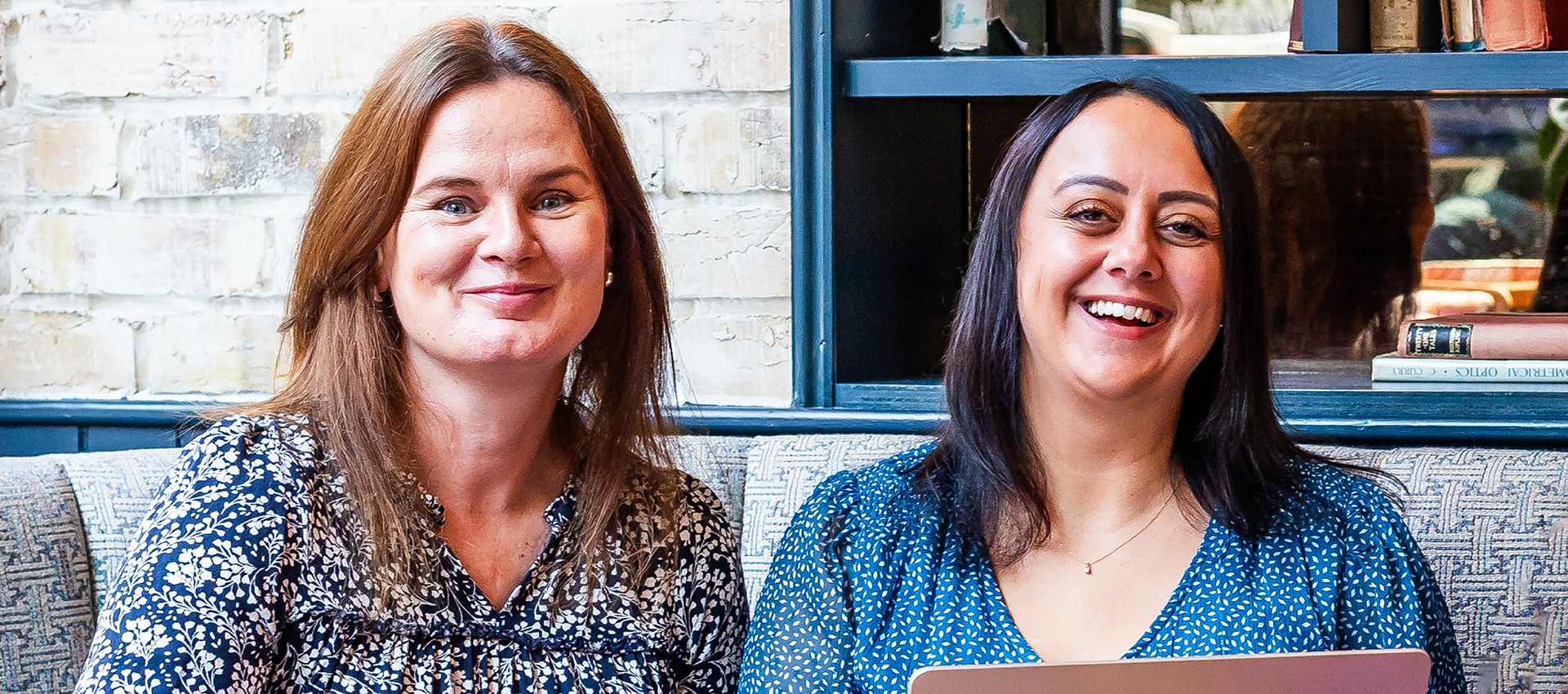 Emma Culver & Bianca Rodriguez Jacobs of KBE Partners sitting at a round table with open laptop.