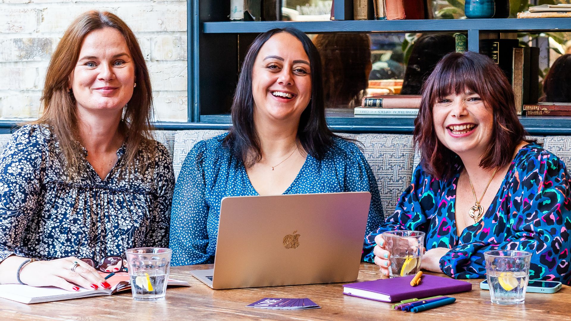 Emma Culver, Bianca Rodriguez Jacobs and Katie Bell of KBE Partners sitting at a round table with open laptop and glasses of water.