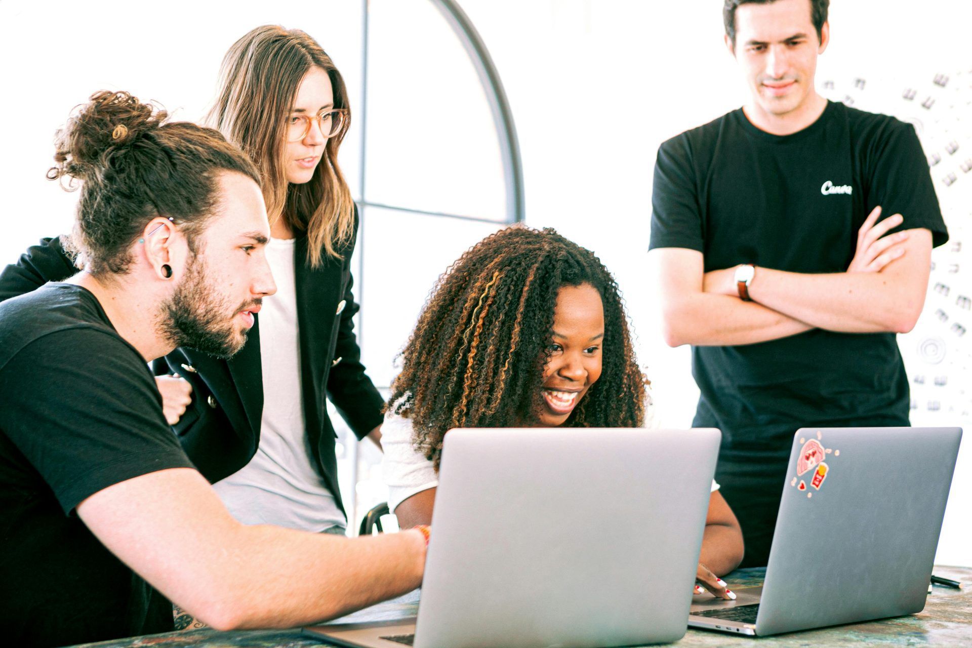 Diverse colleagues smiling around a laptop
